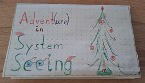Photo of the front page of my zine featuring a drawing of a Christmas tree and the title “Advent(ure) in System Seeing”. There are 4 red balls on the tree, with the digits 2, 0, 2, and 5 on them. There are electric lights, too, and the picture shows the cable and where it is plugged into the wall socket.